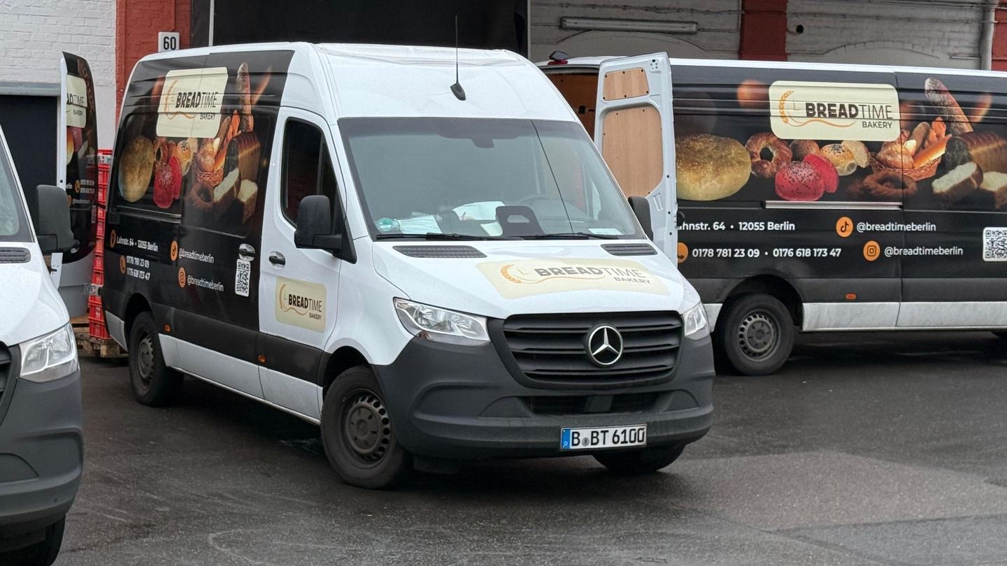 Zwei Lieferwagen mit Breadtime-Beschriftung stehen auf dem Hof vor der geöffneten Ladetür.